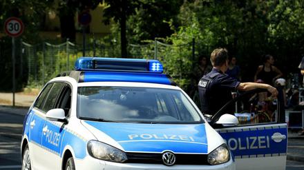Ein Polizist neben einem Polizeiauto.