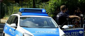 Ein Polizist neben einem Polizeiauto.