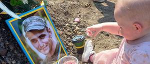 An ihrem ersten Geburtstag frühstückt das Mädchen am Grad seines Vaters.