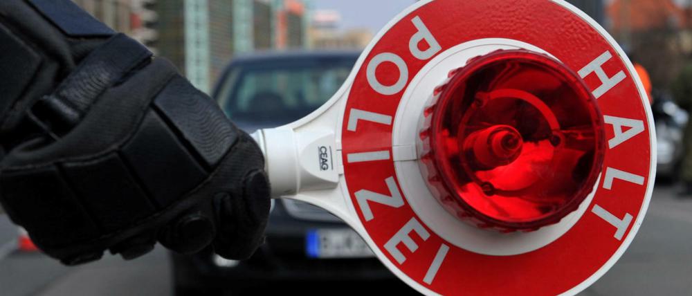 Ein Polizist hält bei einer Sonderkontrolle eine Polizeikelle.