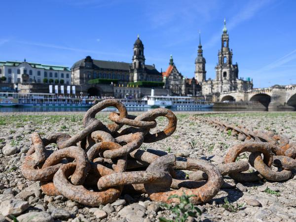 Ein trockengefallenes Flussufer mit Altstadt im Hintergrund.