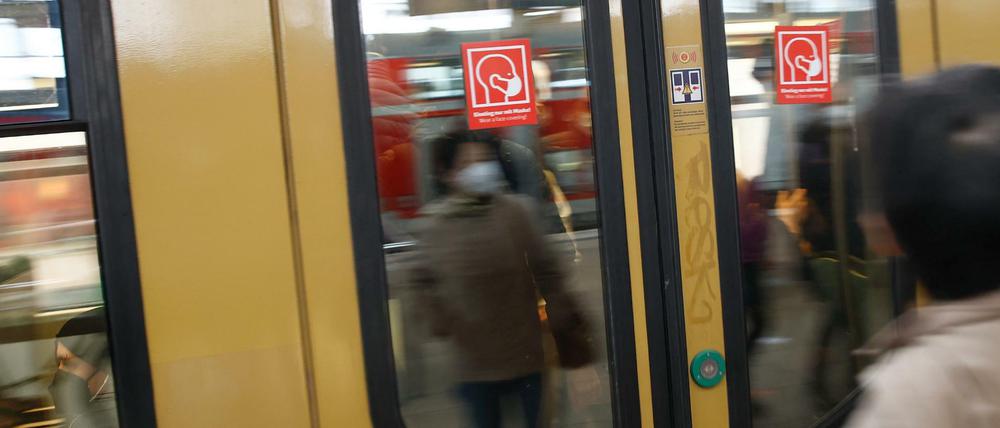 Rote Schilder weisen auf der S-Bahn Tür auf die Pflicht zum Tragen einer Maske hin.
