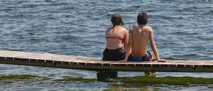 Zwei Badegäste sitzen auf einem Steg am Storkower See (Archivbild).