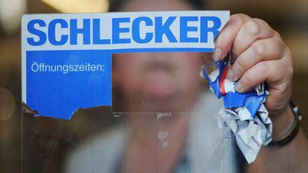 Eine Mitarbeiterin der Drogeriemarktkette Schlecker reißt das Firmenlogo von der Eingangstür einer Filiale. 