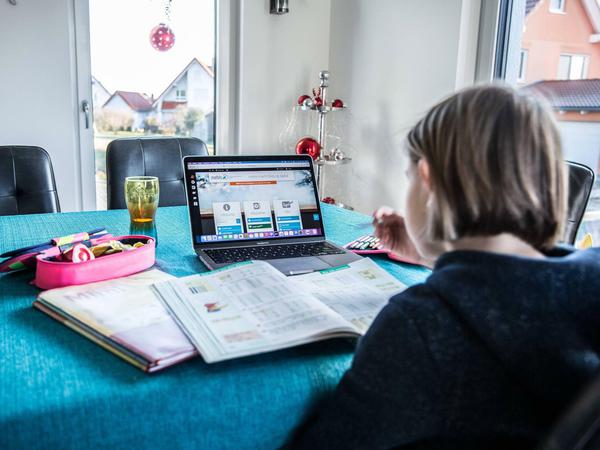 Eine Schülerin arbeitet zu Hause am Esstisch an ihrem Laptop.