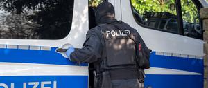 Ein Polizist steht im Rahmen einer Razzia gegen Rechtsextremisten an einem Einsatzfahrzeug.