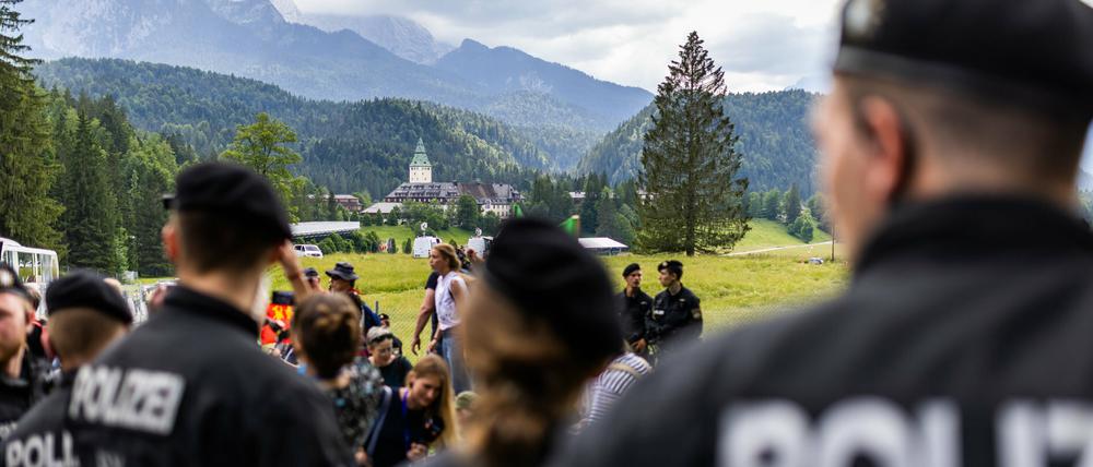 Eine Gruppe von Polizisten in Sichtweite von Schloss Elmau (im Hintergrund) beobachtet eine Demonstration. 