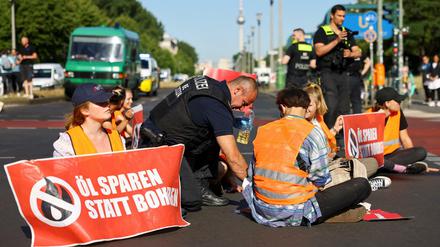 Festgeklebt auf der Fahrbahn: Ein Polizist versucht die Hand eines Aktivisten vom Asphalt am Frankfurter Tor zu lösen.