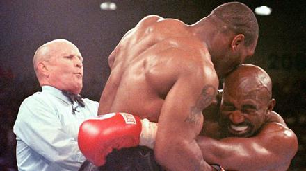 Der Moment danach. Evander Holyfield (rechts) verzieht das Gesicht vor Schmerz, nachdem ihm Mike Tyson einen Teil des rechten Ohres abgebissen hat.