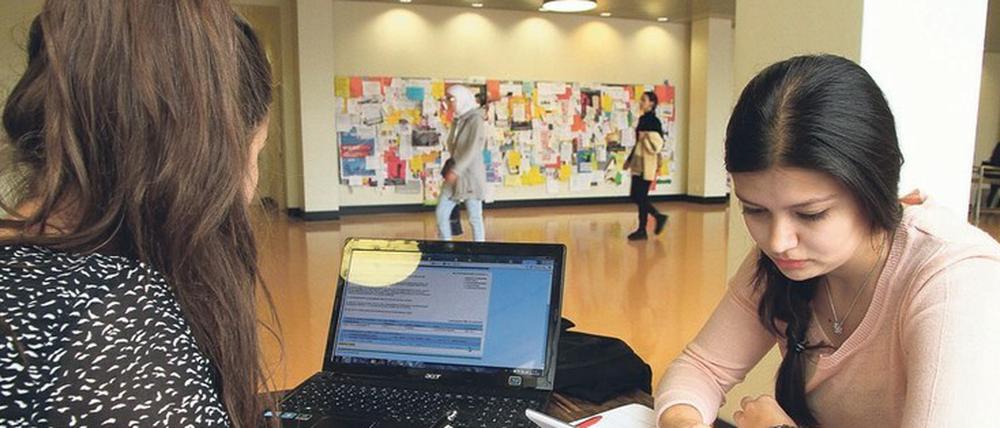 Zwei junge Studentinnen lernen am Rande des Foyers der Silberlaube der Freien Universität im Gang.