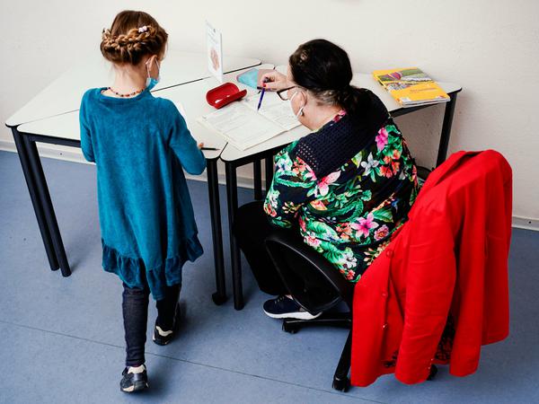 Ein Mädchen arbeitet mit ihrer Nachhilfelehrerin in einem Aufgabenheft.