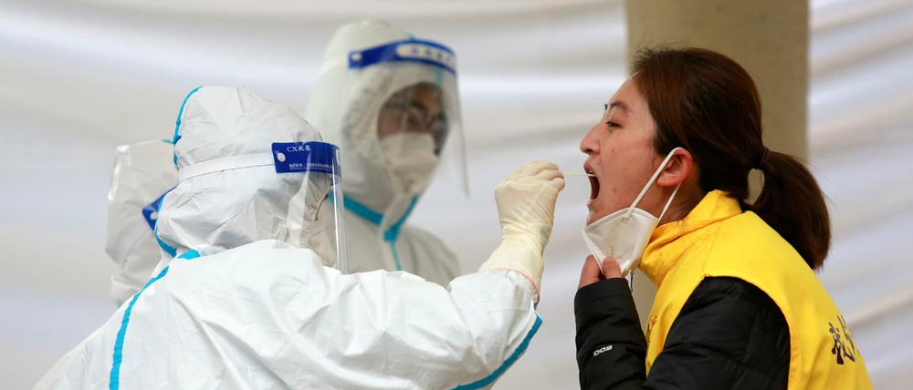 Arbeiter in Schutzanzügen nehmen am 6. Januar 2022 einer Frau in Xi'an eine Probe für einen COVID-19-Test ab.