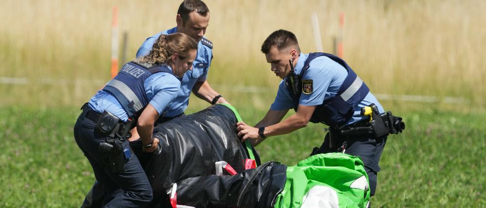 Polizeibeamte transportieren die Hülle einer Hüpfburg ab. Das Spielgerät war bei einem Fest auf dem Sportplatz von Gondershausen von einer Windböe erfasst und mindestens vier Meter in die Höhe gehoben worden.