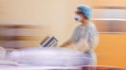 Eine Assistenzärztin schiebt auf einer Intensivstation das Krankenbett eines Covid-19-Patienten. 