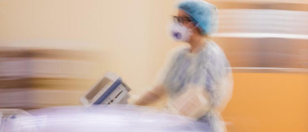 Eine Assistenzärztin schiebt auf einer Intensivstation das Krankenbett eines Covid-19-Patienten.