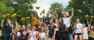 Kinder und Jugendliche, die vom Bezirksamt für ihre Engagement geehrt wurden, halten Sonnenblumen in der Hand und springen gemeinsam hoch.