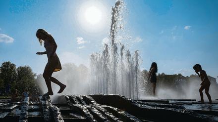 Kinder kühlen sich am Brunnen ab.