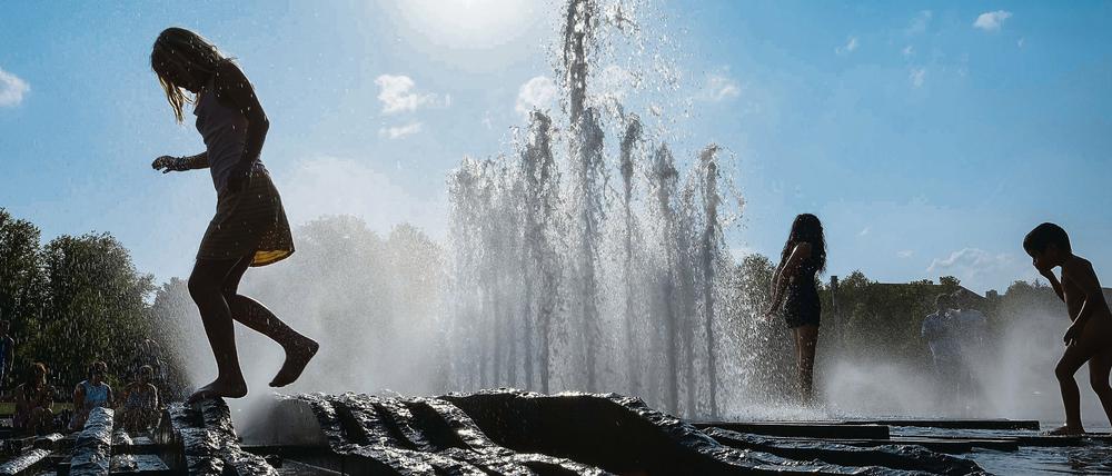 Kinder kühlen sich am Brunnen ab.