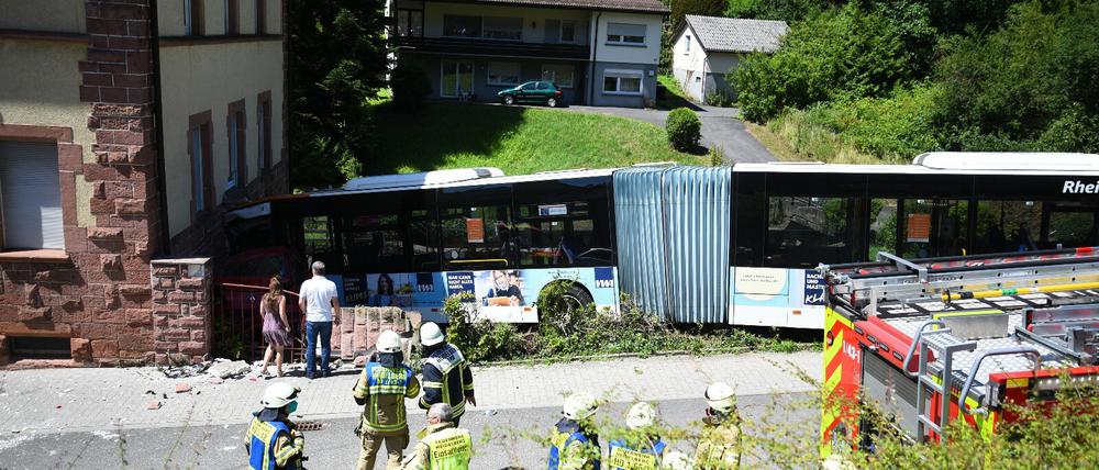 Einsatzkräfte begutachten eine Unfallstelle an der ein Linienbus gegen ein Wohnhaus gefahren ist.