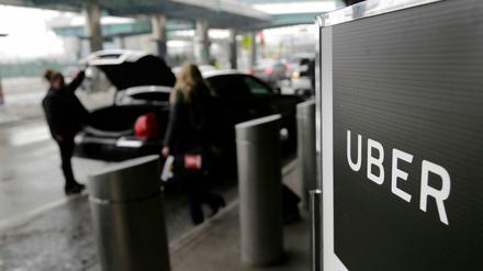 Ein Schild mit dem Logo des amerikanischen Dienstleistungsunternehmens Uber steht am Abholpunkt von Uber auf dem LaGuardia-Flughafen (Symbolbild).