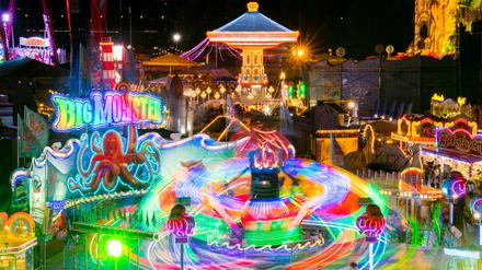 Bei einer Kirmes in Düsseldorf dreht sich ein Karussell im Abendlicht. 