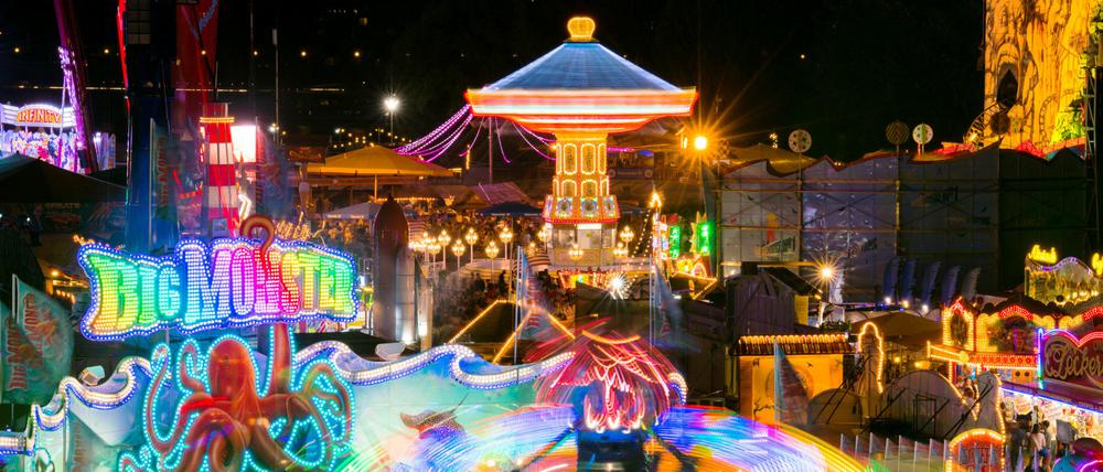 Bei einer Kirmes in Düsseldorf dreht sich ein Karussell im Abendlicht.