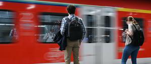 Zugreisende warten im Frankfurter Hauptbahnhof auf die Einfahrt einer S-Bahn.