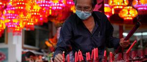 Ein Gläubiger hält Räucherstäbchen und stellt eine Kerze in einen Tempel anlässlich des chinesischen Neujahrsfest. 
