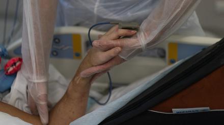 Eine Krankenschwester hält die Hand eines Coronavirus-Patienten