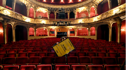 Kultur in Corona-Zeiten. Eine Angestellte trägt ein 2G-Schild durch den Saal.
