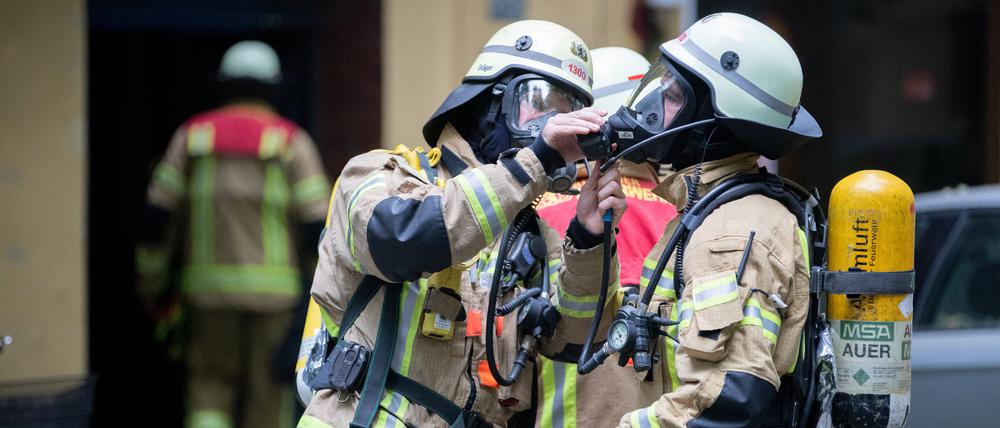 Feuerwehrleute befestigen ihre Atemmasken.