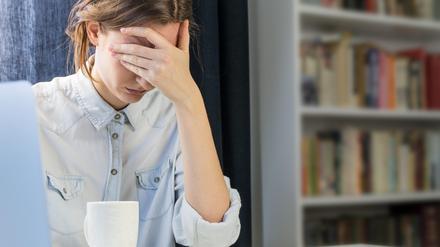 Eine erschöpfte Studentin sitzt zu Hause an ihrem Laptop.