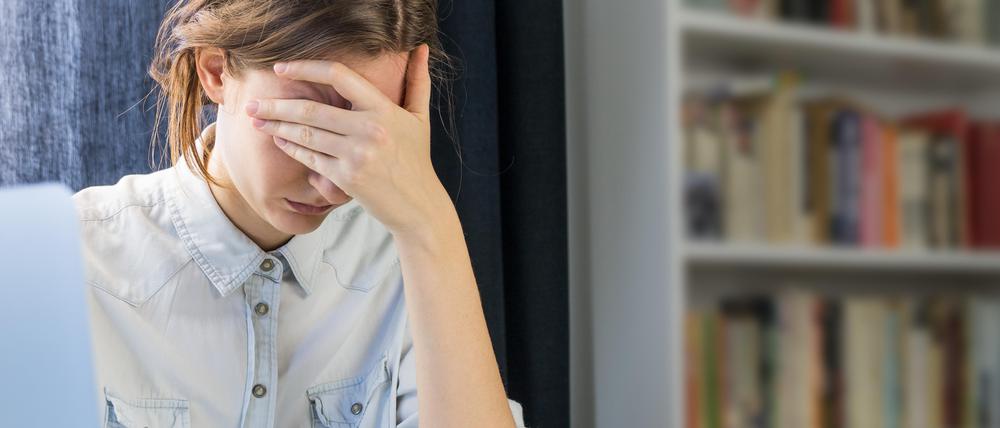 Eine erschöpfte Studentin sitzt zu Hause an ihrem Laptop.