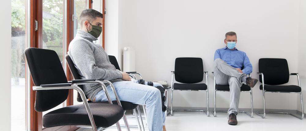 Patienten warten im Wartezimmer einer Arztpraxis. Deutschlands Kassenärzte wollen sich in der Coronakrise als eine Art Bollwerk vor die Krankenhäuser stellen.
