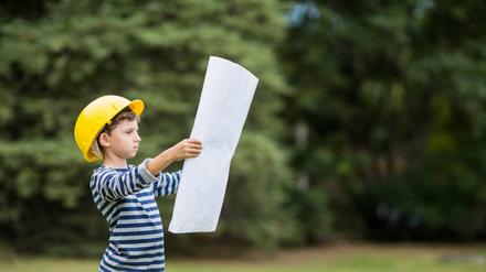 Boy in hard hat reading a plan.