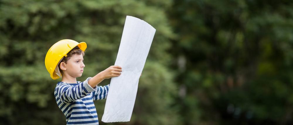 Boy in hard hat reading a plan.