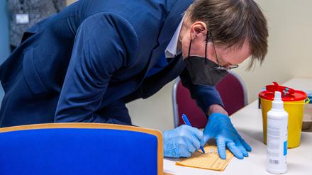17.01.2022, Mecklenburg-Vorpommern, Schwerin: Karl Lauterbach (SPD), Bundesgesundheitsminister, unterschreibt den Impfausweis, nachdem er einen Patienten im Impfzentrum in der Sport- und Kongresshalle mit dem Impfstoff von BioNTech/Pfizer geimpft hat. Lauterbach informiert sich in Mecklenburg-Vorpommern über den Verlauf der Corona-Impfungen und die Umsetzung der Schutzmaßnahmen. Foto: Jens Büttner/dpa Pool/dpa +++ dpa-Bildfunk +++
