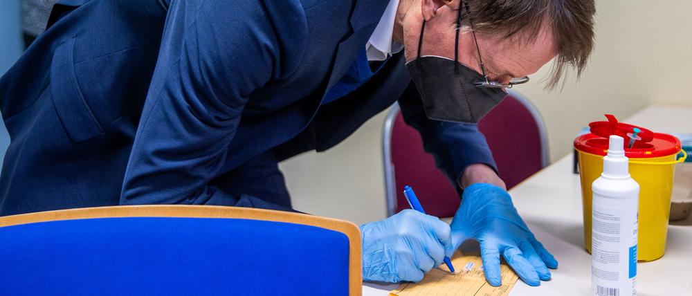 Karl Lauterbach unterschreibt im Januar 2022 einen Impfausweis, nachdem er einem Patienten den Corona-Impfstoff von Biontech verabreicht hat.