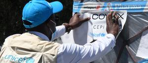 ARCHIV - 16.05.2021, Tunesien, Tunis: Ein Mitarbeiter der Vereinten Nationen überprüft eine neue Charge von Corona-Impfstoffen, geliefert im Rahmen der globalen COVAX-Initiative, am Internationalen Flughafen Karthago und befestigt einen Zettel daran. (zu dpa "im Rahmen der globalen COVAX-Initiative") Foto: Adel Ezzine/XinHua/dpa +++ dpa-Bildfunk +++