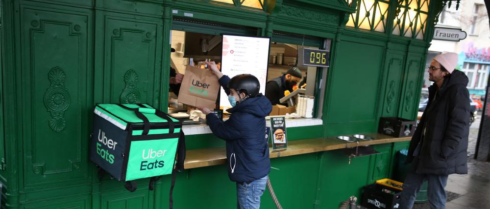 Ein Fahrer von Uber Eats am Burgermeister-Imbiss am Schlesischen Tor eine Lieferung ab.
