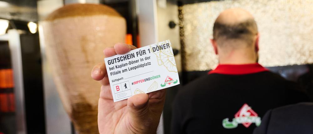 «Gutschein für 1 Döner» steht auf einem Flyer, den Döner-Besitzer Kaplan in seinem Döner Imbiss hält. Im Rahmen des kreativen Impfens macht Berlin auch in der bundesweiten Aktionswoche niedrigschwellige Walk-In Impfangebote. Dort Geimpfte erhalten einen Dönergutschein.