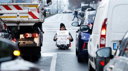 Ein Aktivist zeigt ein Schild mit der Aufschrift „Lieber Wegsperren als Reden“ bei einer Sitzblockade mit weiteren Aktivisten auf der Prenzlauer Allee. Neben dem Protest für mehr Umweltschutz demonstrierten die Teilnehmer auch gegen die Festnahme von anderen Aktivisten. 