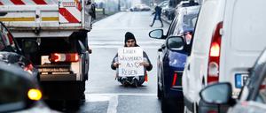 Ein Aktivist zeigt ein Schild mit der Aufschrift „Lieber Wegsperren als Reden“ bei einer Sitzblockade mit weiteren Aktivisten auf der Prenzlauer Allee. Neben dem Protest für mehr Umweltschutz demonstrierten die Teilnehmer auch gegen die Festnahme von anderen Aktivisten. 