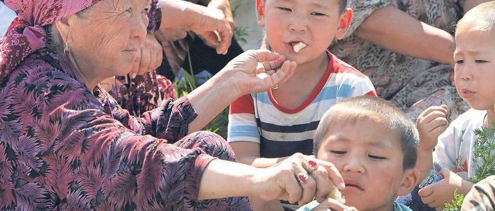 Selbsthilfe. Eine Frau verteilt Brot an Kinder – Szene aus einem Flüchtlingslager in Südkirgistan diese Woche.Foto: Maxim Shipenkov/epa