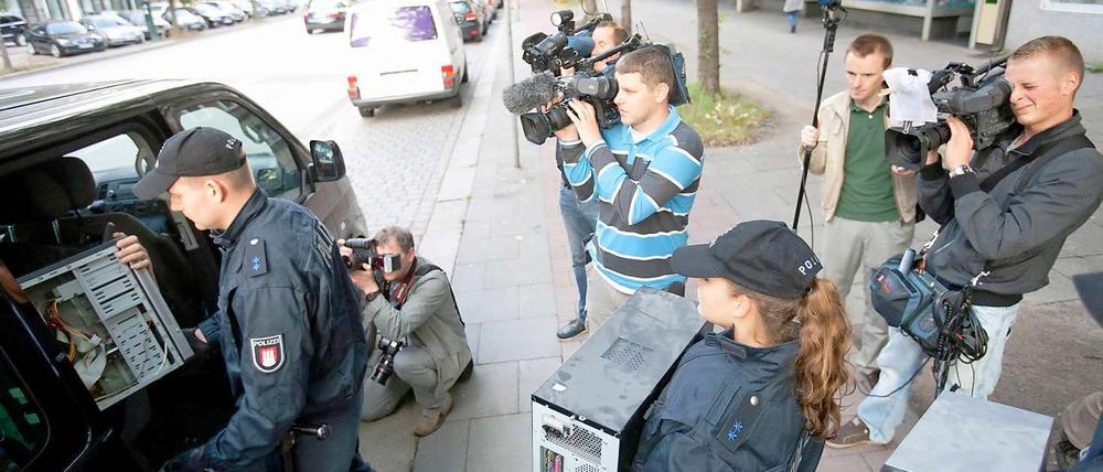 Polizisten tragen in Hamburg Computer aus dem Gebäude der Moschee.