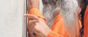 Blick zurück. Indische Mitglieder der Religionsgemeinschaft „Ananda Marga“ schauten Freitag an der Gedenkstätte Bernauer Straße, nach der Gedenkveranstaltung zum 49. Jahrestags des Mauerbaus, durch einen Spalt des Betonwalls. Foto: Lennart Preiss/ddp