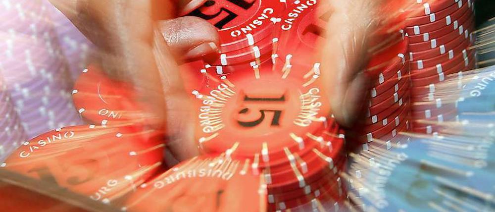 Eine Hand greift nach Jetons. Der Betrieb von Automatencasinos boomt in Berlin.