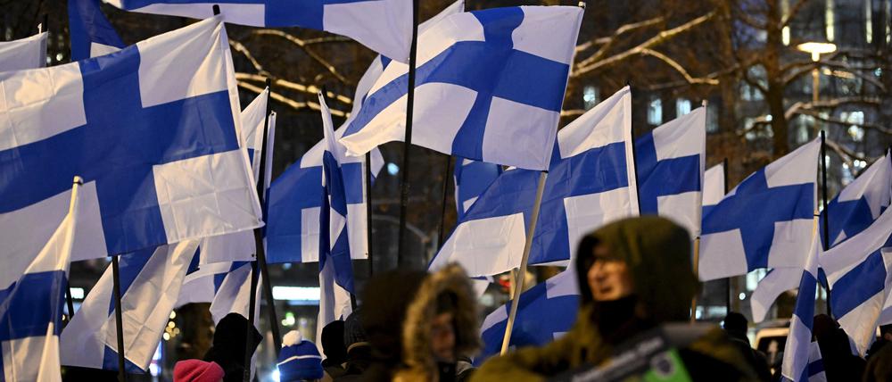 Feiernde schwenken finnische Nationalfahnen bei einer Parade zum finnischen Unabhängigkeitstag in Helsinki. 