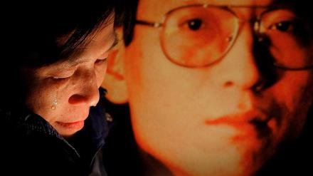 Eine Aktivistin neben einem Foto von Liu Xiaobo.