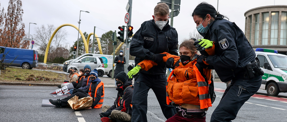 Polizisten tragen einen Blockierer von der Straße. Die Aktivisten wollen ein Essen-Retten-Gesetz.